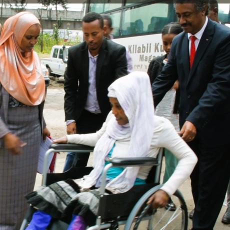 State Minister Dr. Abraha and ActionAid Representative Mr. Dechassa helping Abeba move the wheelchair