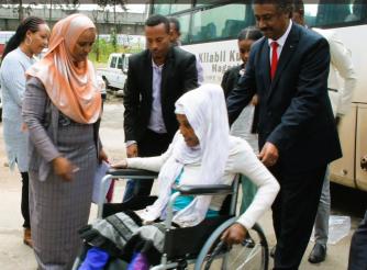 State Minister Dr. Abraha and ActionAid Representative Mr. Dechassa helping Abeba move the wheelchair